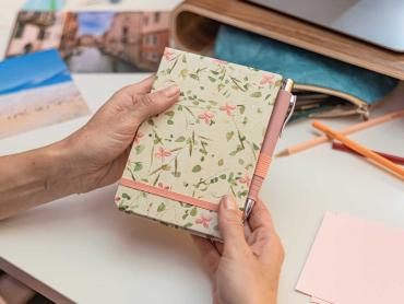 Frau hält Jolie Reporterblock mit Blumenmuster in den Händen