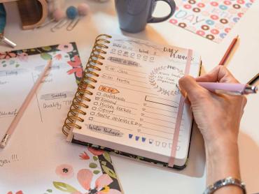 Hand schreibt in Spiral-Kalender