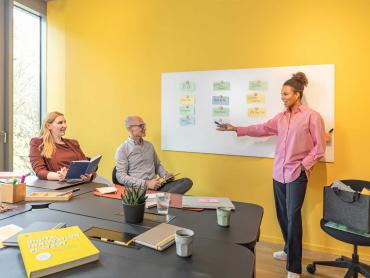 Frau erklärt Kollegen Projekt anhand Whiteboard