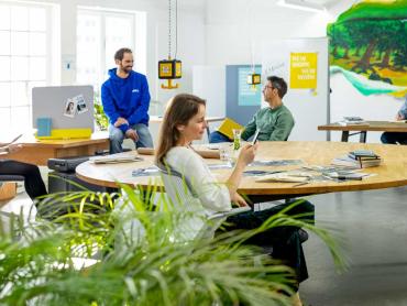 Kollegen sitzen im Büro an unterschiedlichen Arbeitsplätzen