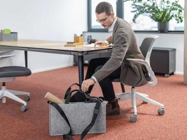Mitarbeiter räumt Desk Sharing Bag aus und richtet Arbeitsplatz ein