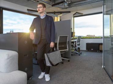 Mitarbeiter steht mit Desk Sharing Bag im Büro
