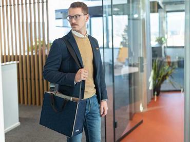 Mann in Büro hat Desk Sharing Bag über Schulter hängen