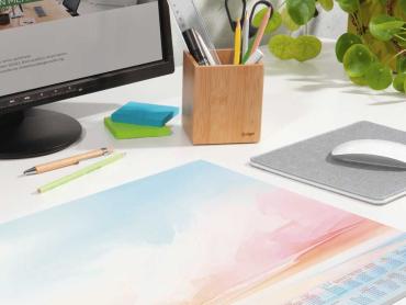 Papier-Schreibunterlage in Watercolor-Optik liegt auf Schreibtisch vor Monitor und neben Mauspad