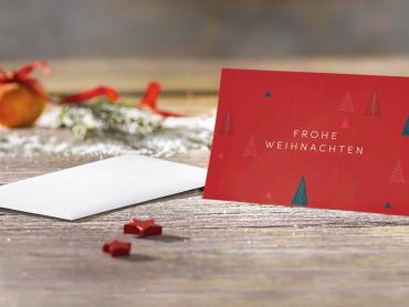 Klappkarte im Format DIN A6 in rot mit Weihnachtsbäumen stehend auf Tischplatte