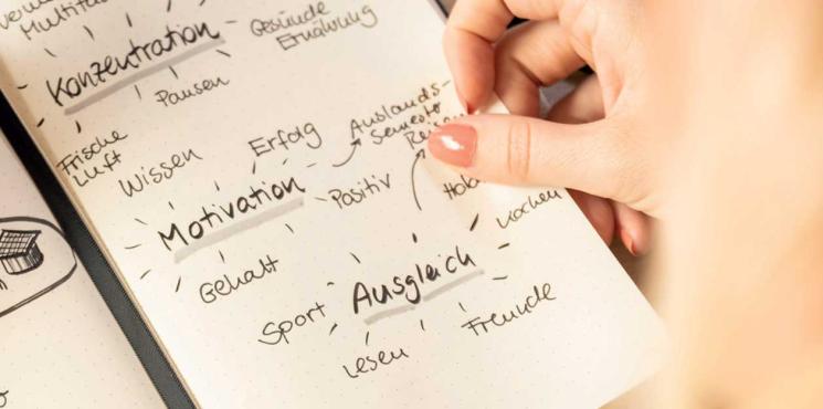 Frau schreibt Notizen zu ihrem Studium in Notizbuch
