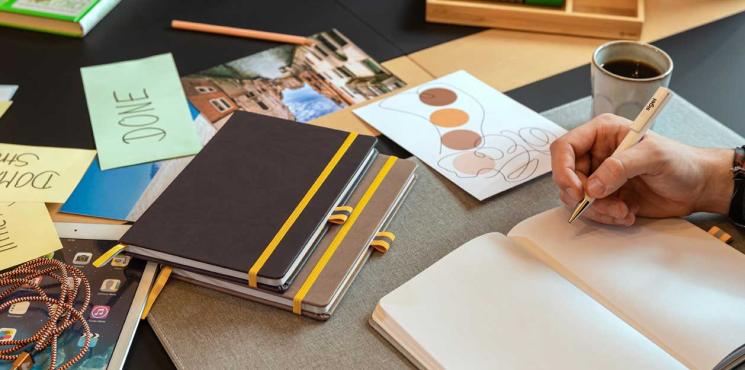 Mann schreibt an Schreibtisch in Notizbuch