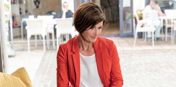 Frau sitzt in Café und schreibt Notizen in Notizbuch