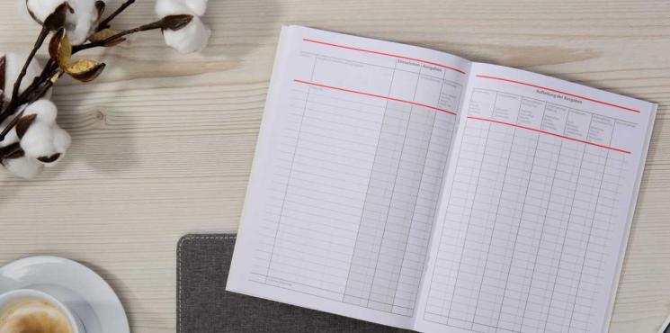 Aufgeschlagenes Haushaltsbuch mit Tasse Kaffee