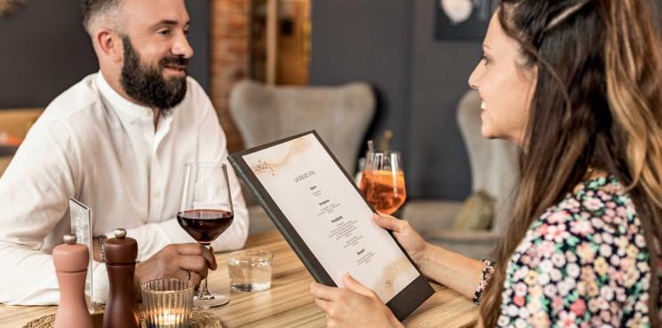 Mann und Frau schauen in Speisekarte in Restaurant
