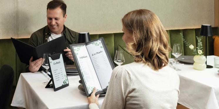 Mann und Frau sitzen in Restaurant und lesen in Speisekarte