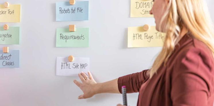 Frau in braunen Blazer steht an Whiteboard
