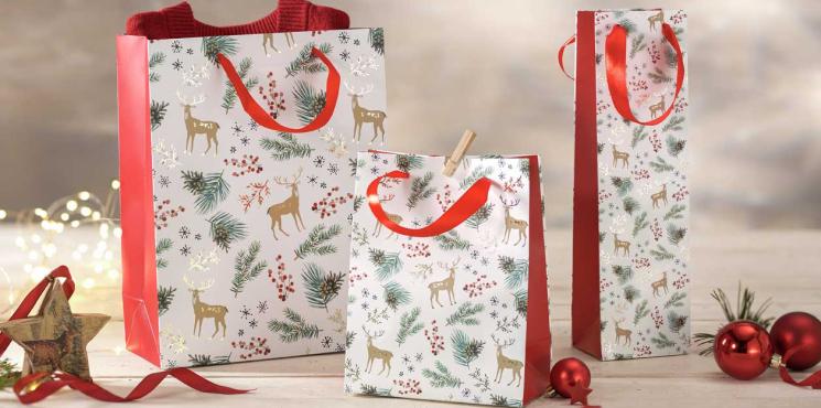 Drei Geschenktaschen mit Hirschen, Tannenzweigen und Tannenzapfen in unterschiedlichen Größen