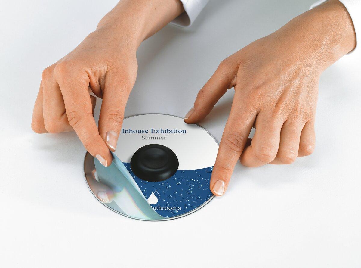 Hands remove a foil from a CD
