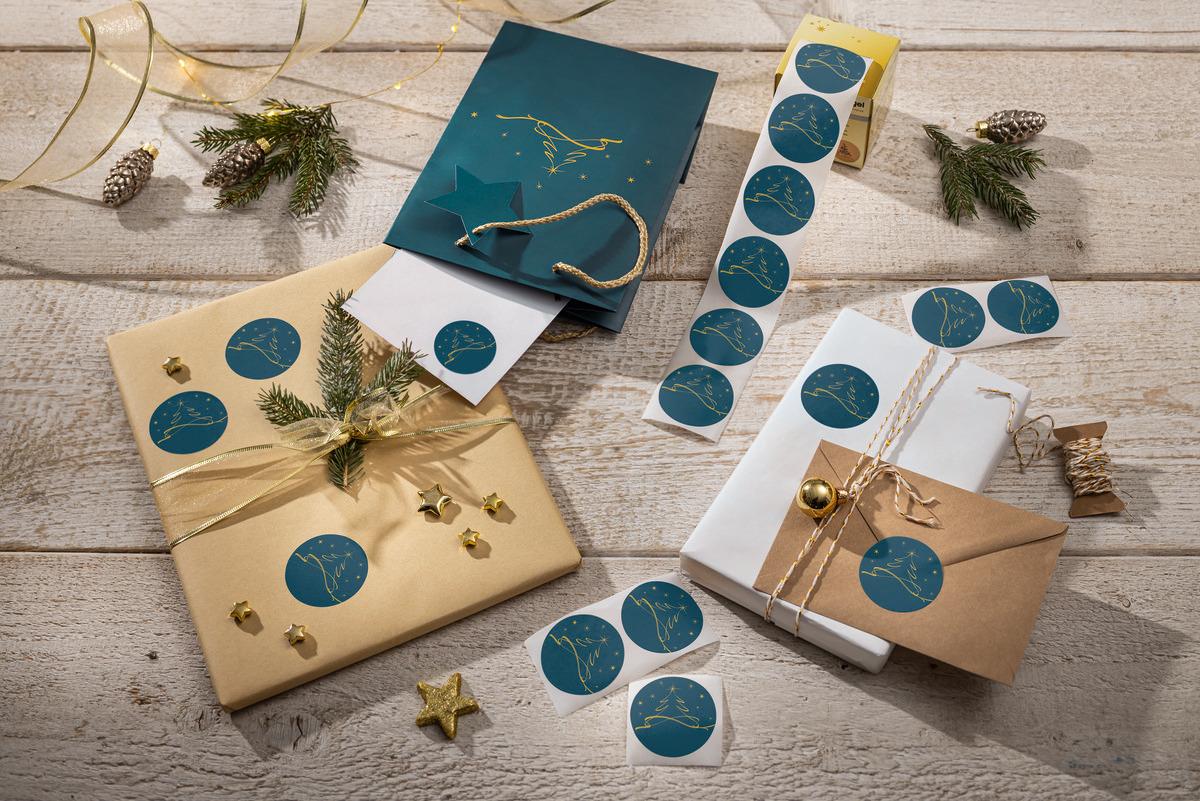 Gift wrapping with blue stickers, coniferous branches and decorative stars on wooden table