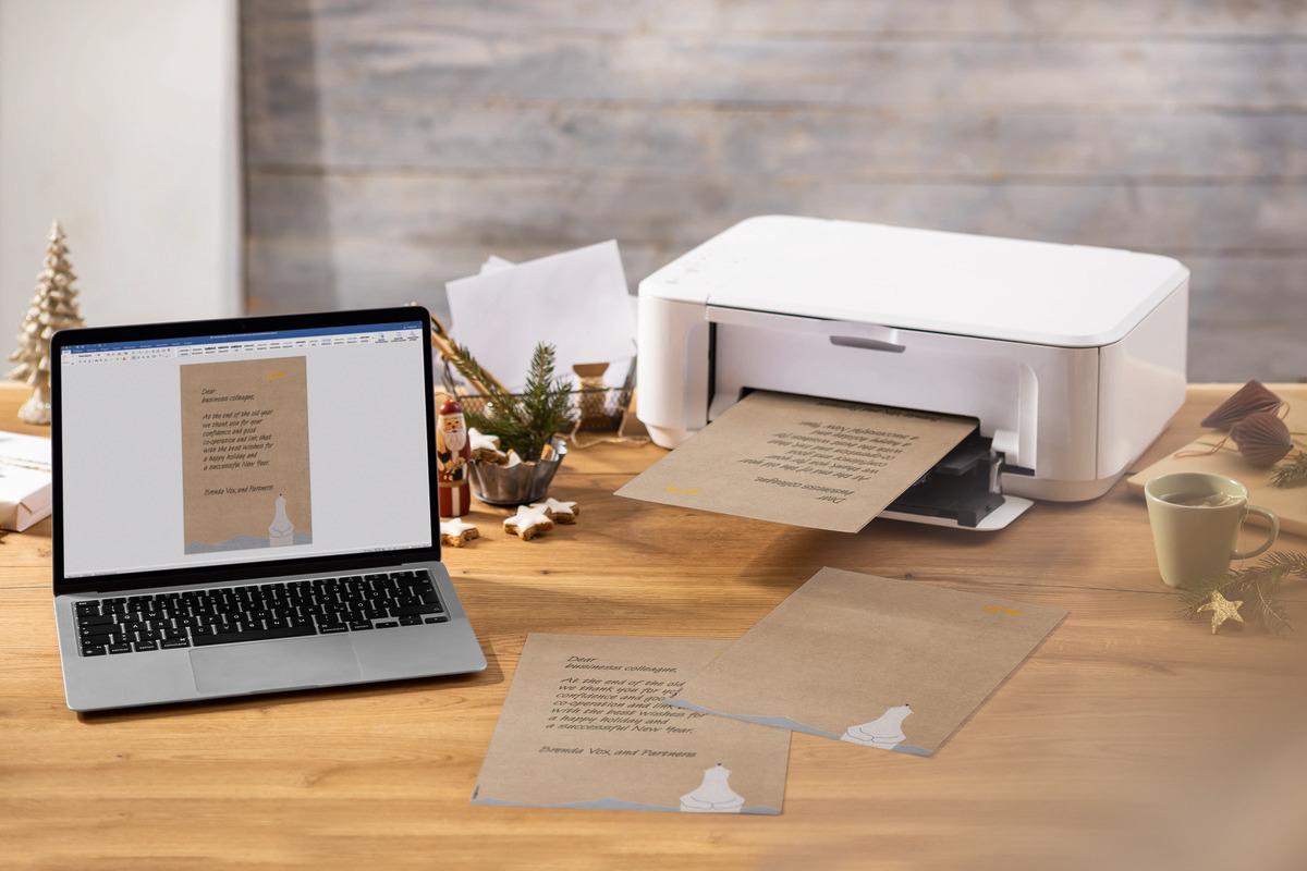 Laptop and printer on wooden table, printing letter
