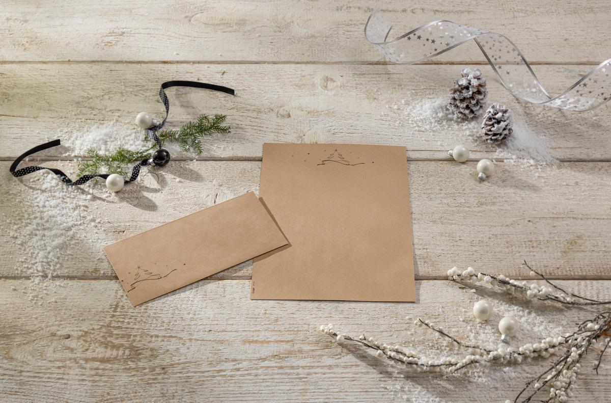 Stationery and envelope on wooden table, decorated with fir branches, cones and ribbon