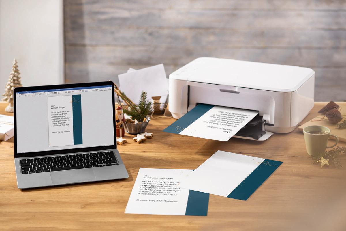 Laptop and printer on desk Christmas decoration and printed document