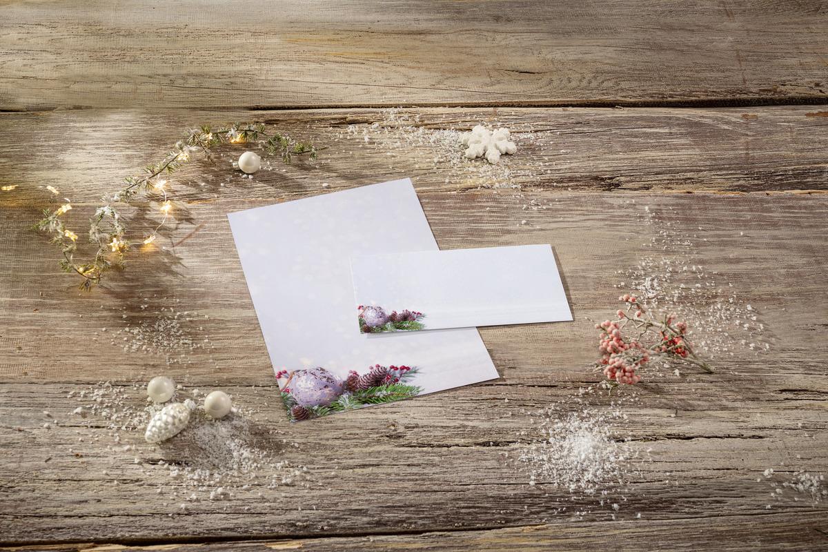 Christmas cards on wooden table, with decorations and fairy lights