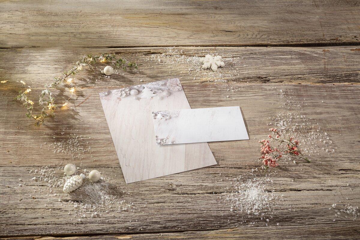 Stationery on wooden table, decorated with fairy lights, red berries and artificial snow
