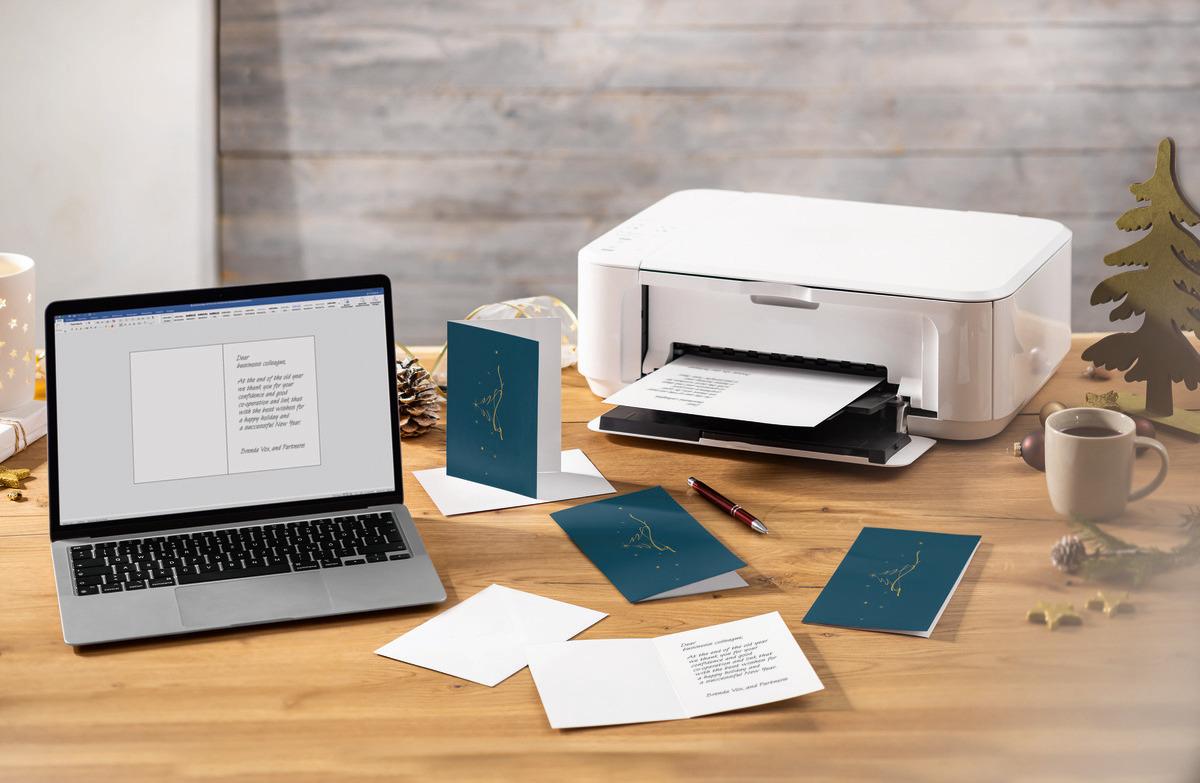 Laptop, printer and greeting cards on a wooden table