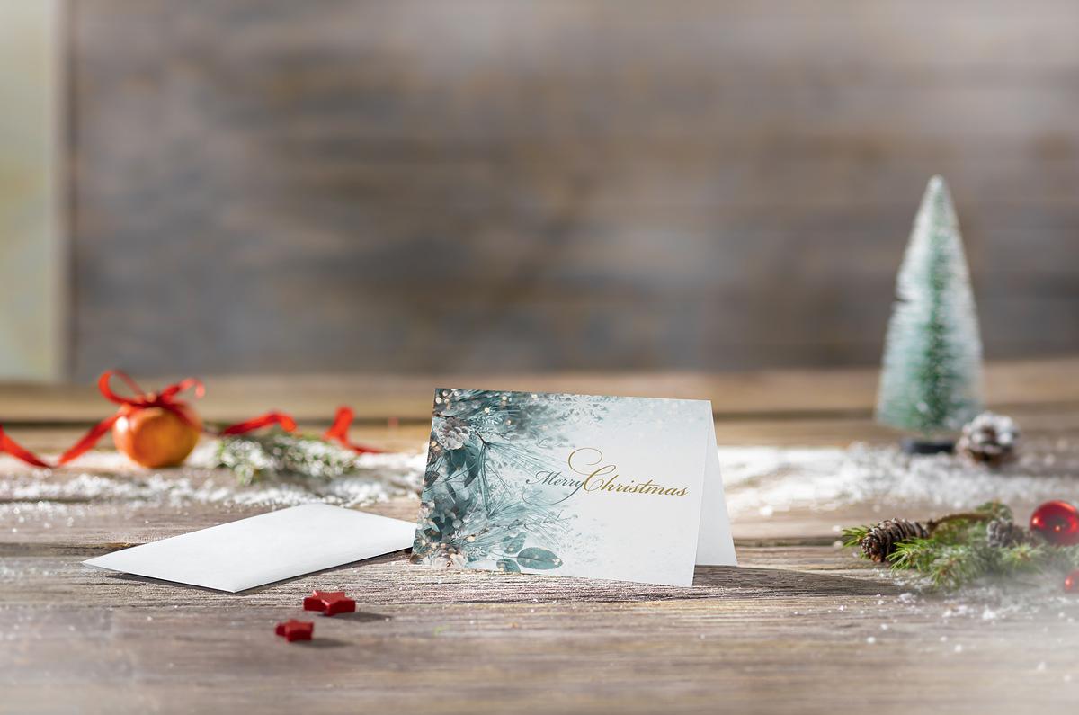 Christmas card on wooden table, decorated with fir branches and baubles