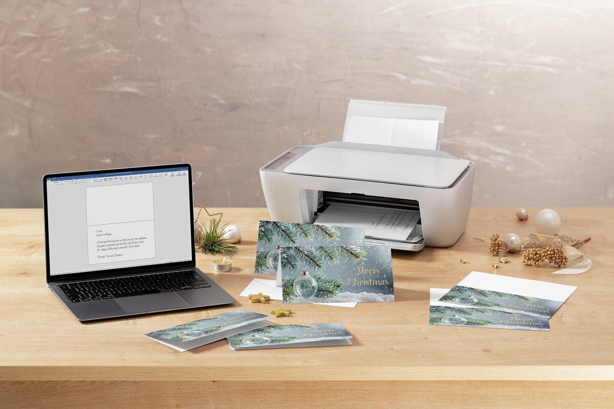 Laptop and printer on table with Christmas cards