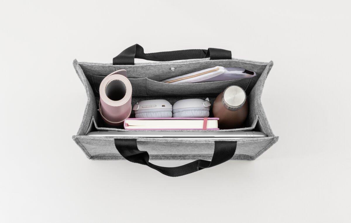Graue Tasche mit Laptop, Notizbuch, Kopfhörern, Trinkflasche und Yogamatte