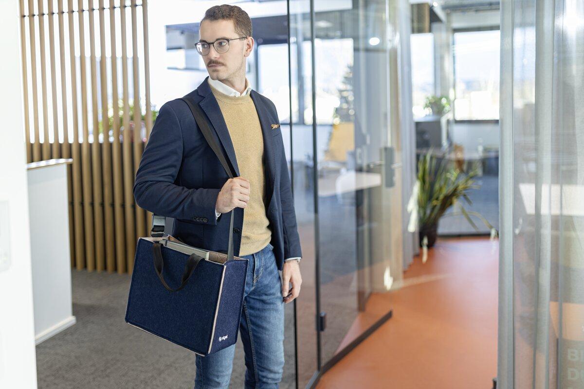 Mann im Büro mit Tasche, schaut zur Seite