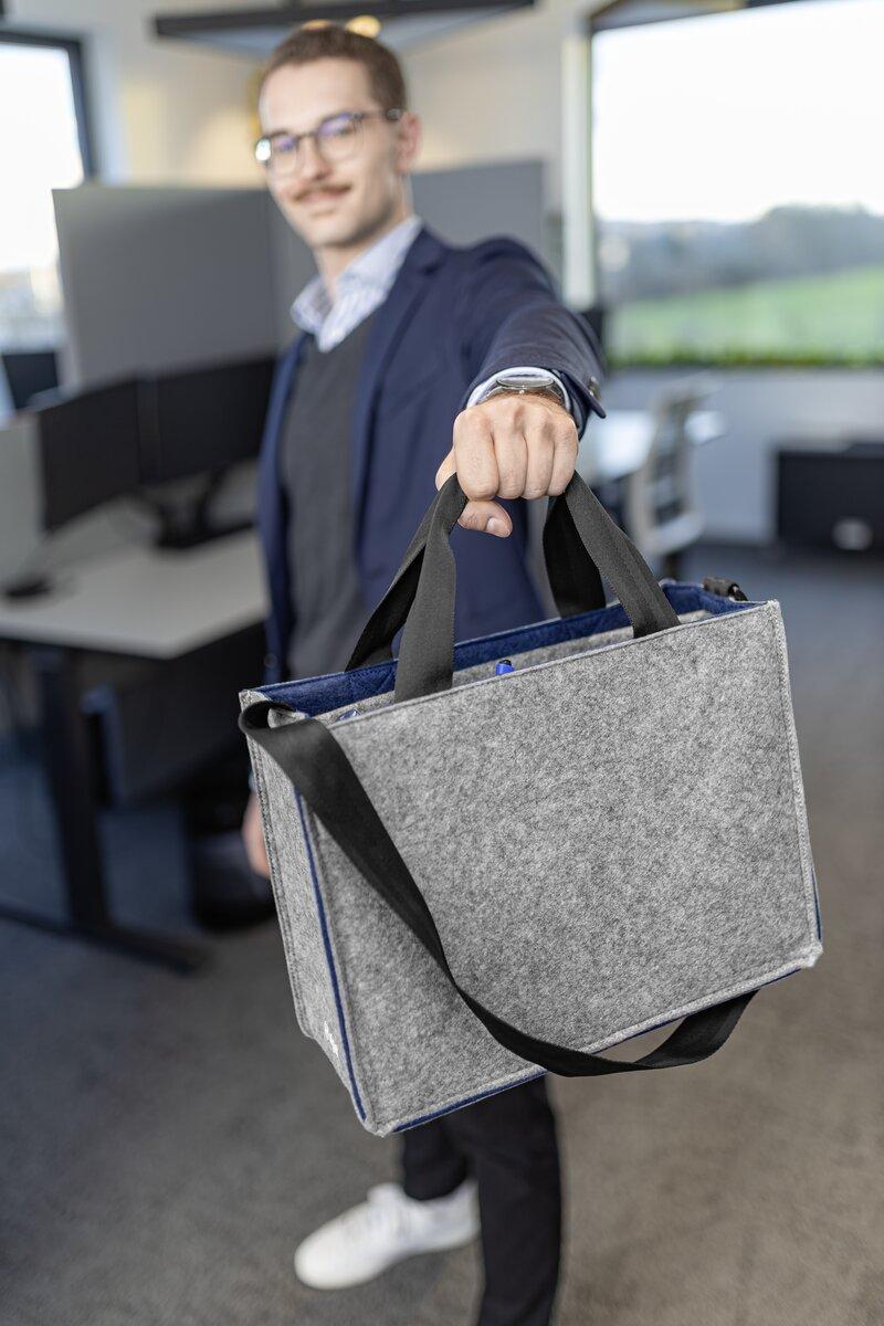 Person im Büro mit grauer Tasche