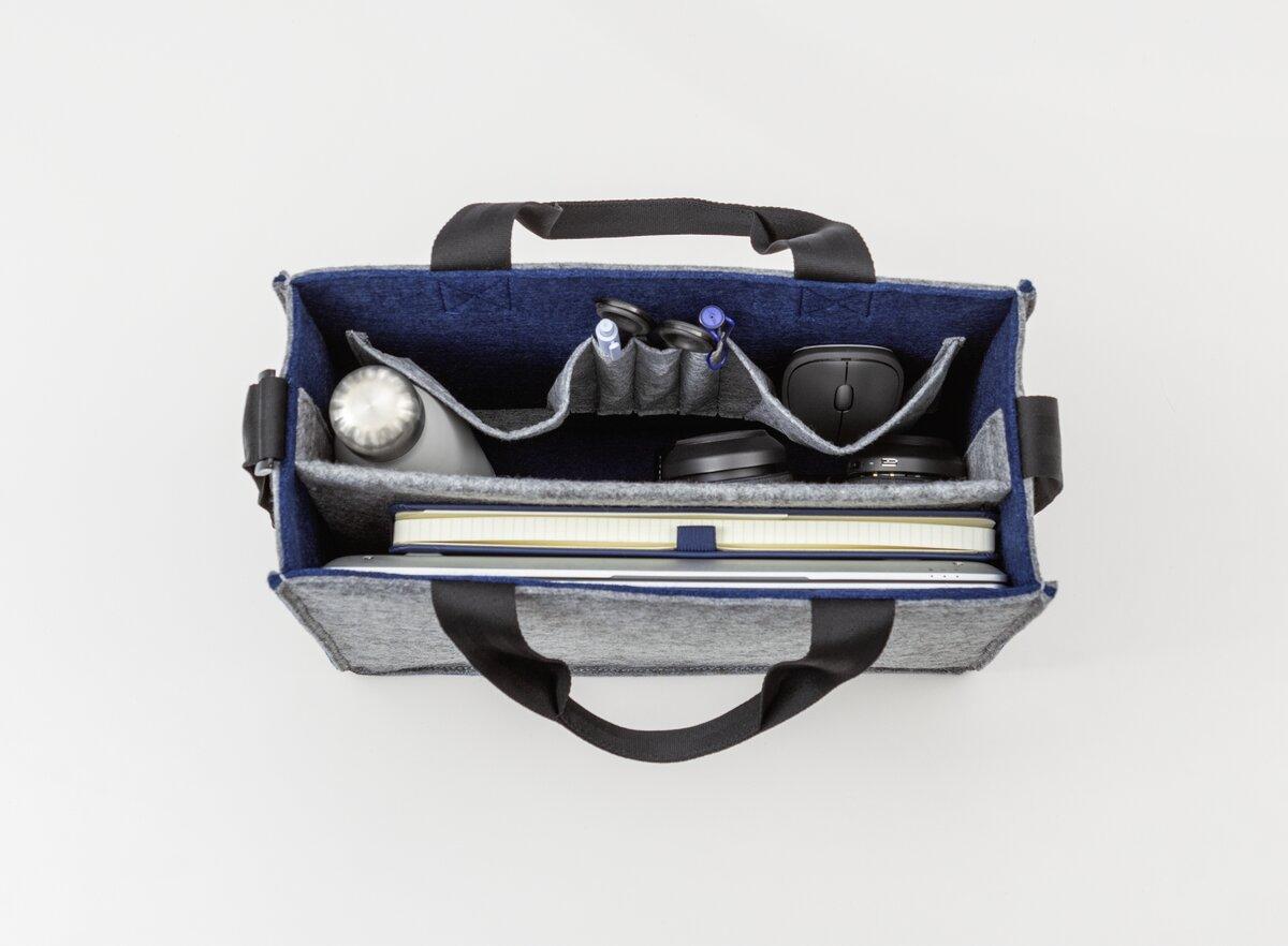 Offene Tasche mit Laptop, Wasserflasche, Kopfhörer und Stiften