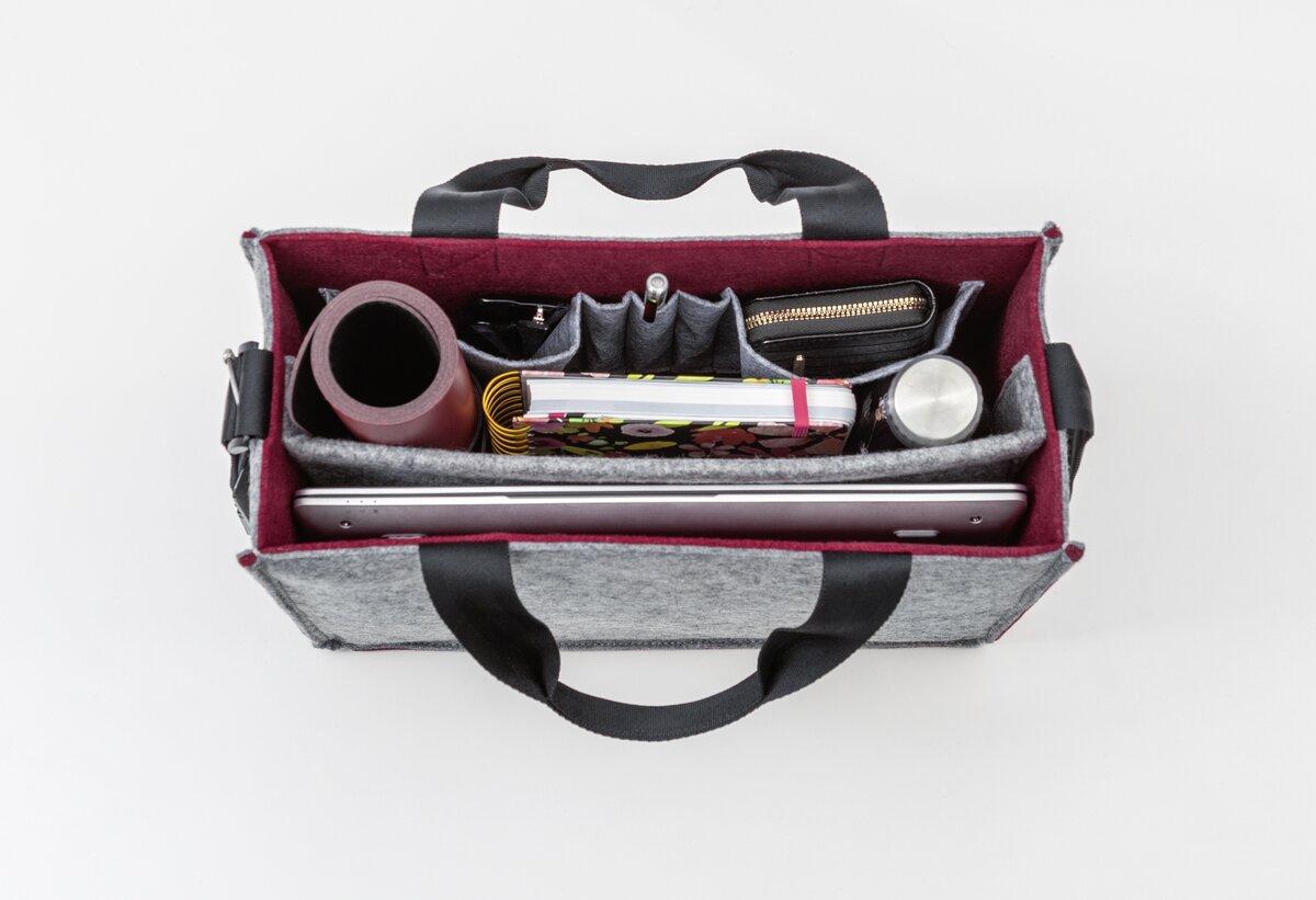 Geöffnete Tasche mit Laptop, Notizbuch, Stift und Becher