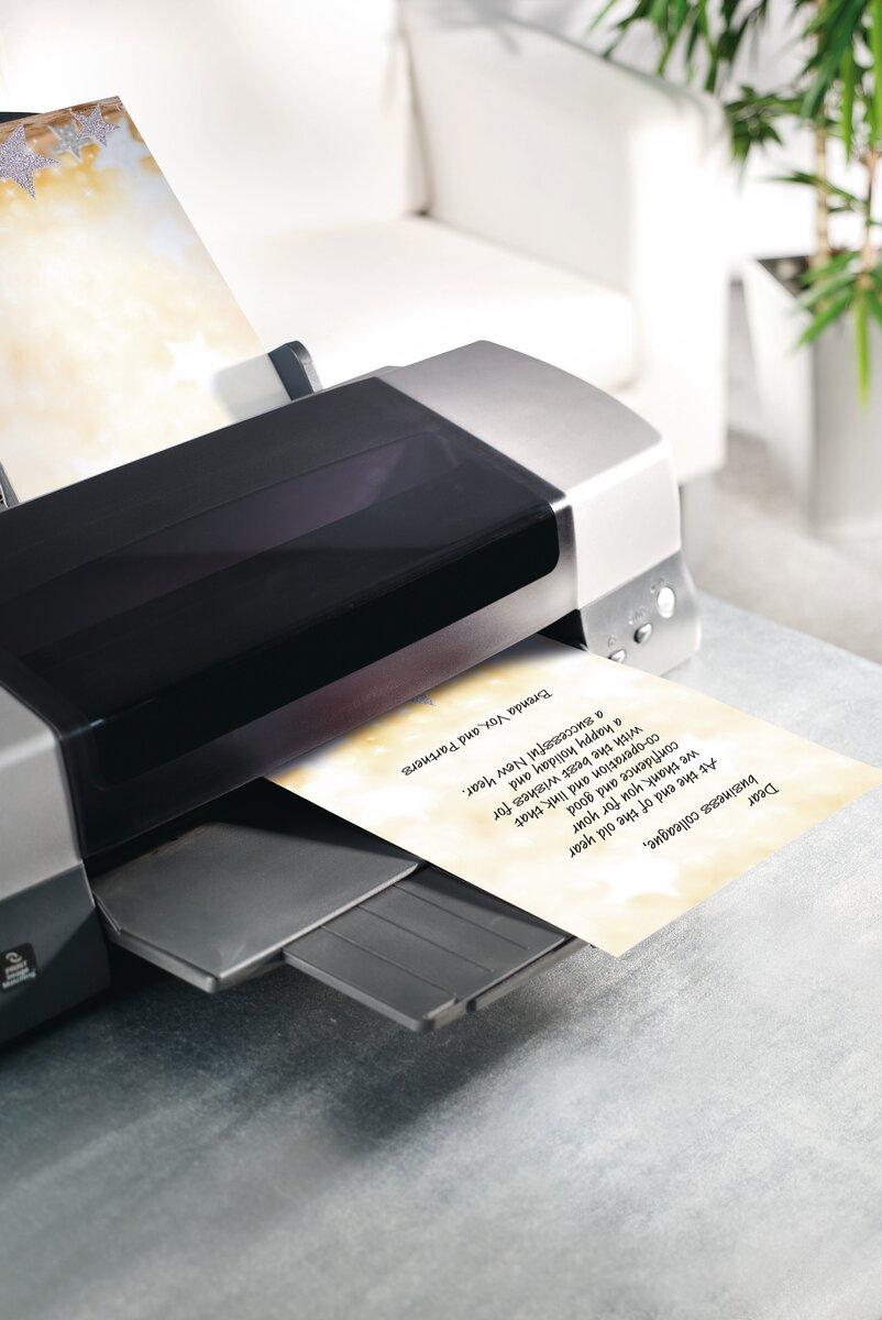 Silver printer with printed paper on a table In the background a white couch and a plant