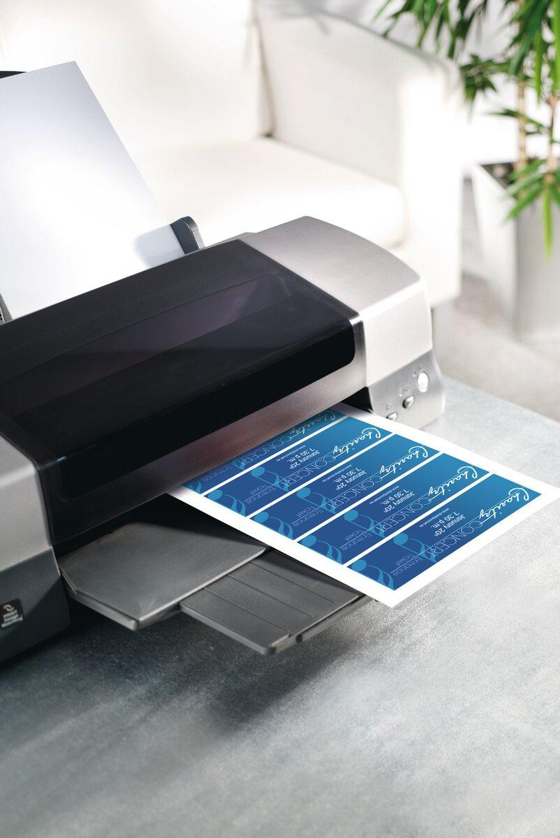 Printer dispensing blue label sheet In the background white couch and plant