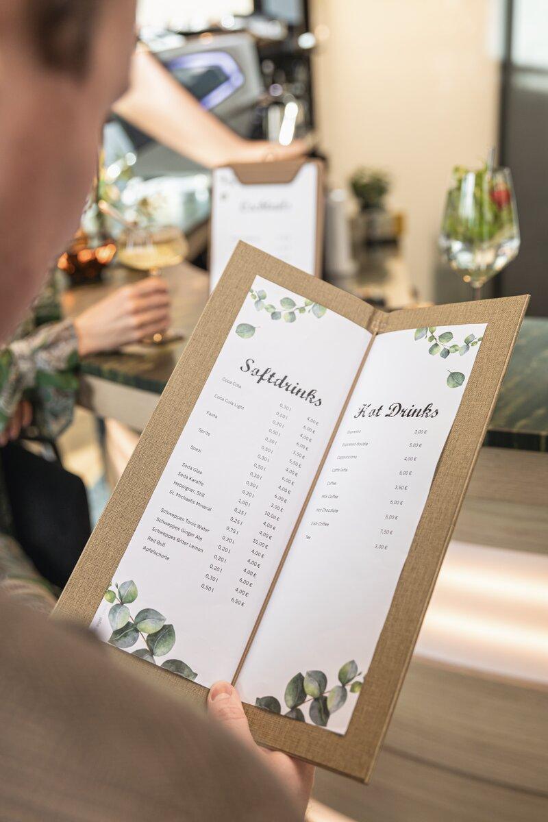 Menu with drink prices, person looks at it