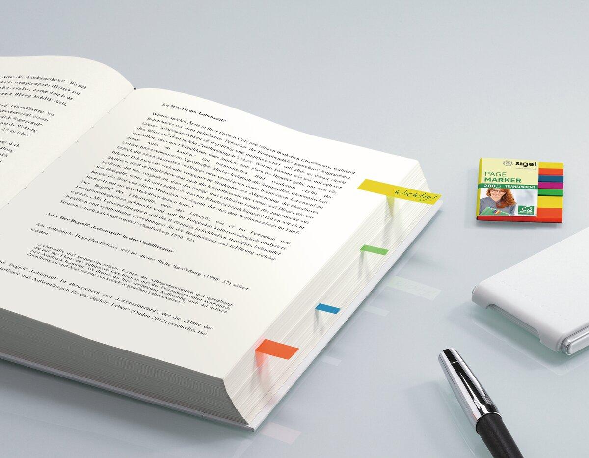 Open book with markers, pen next to it