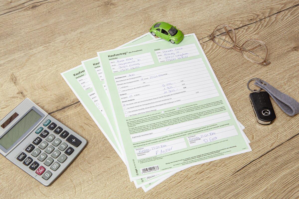 Verträge, Taschenrechner, grünes Spielzeugauto, Brille, Schlüssel auf Holztisch
