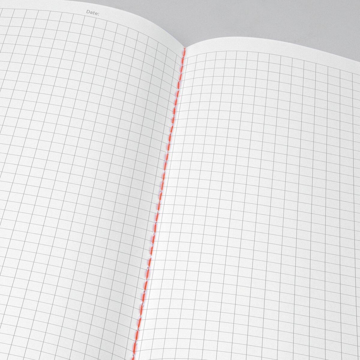 Open notebook with squared paper and red thread