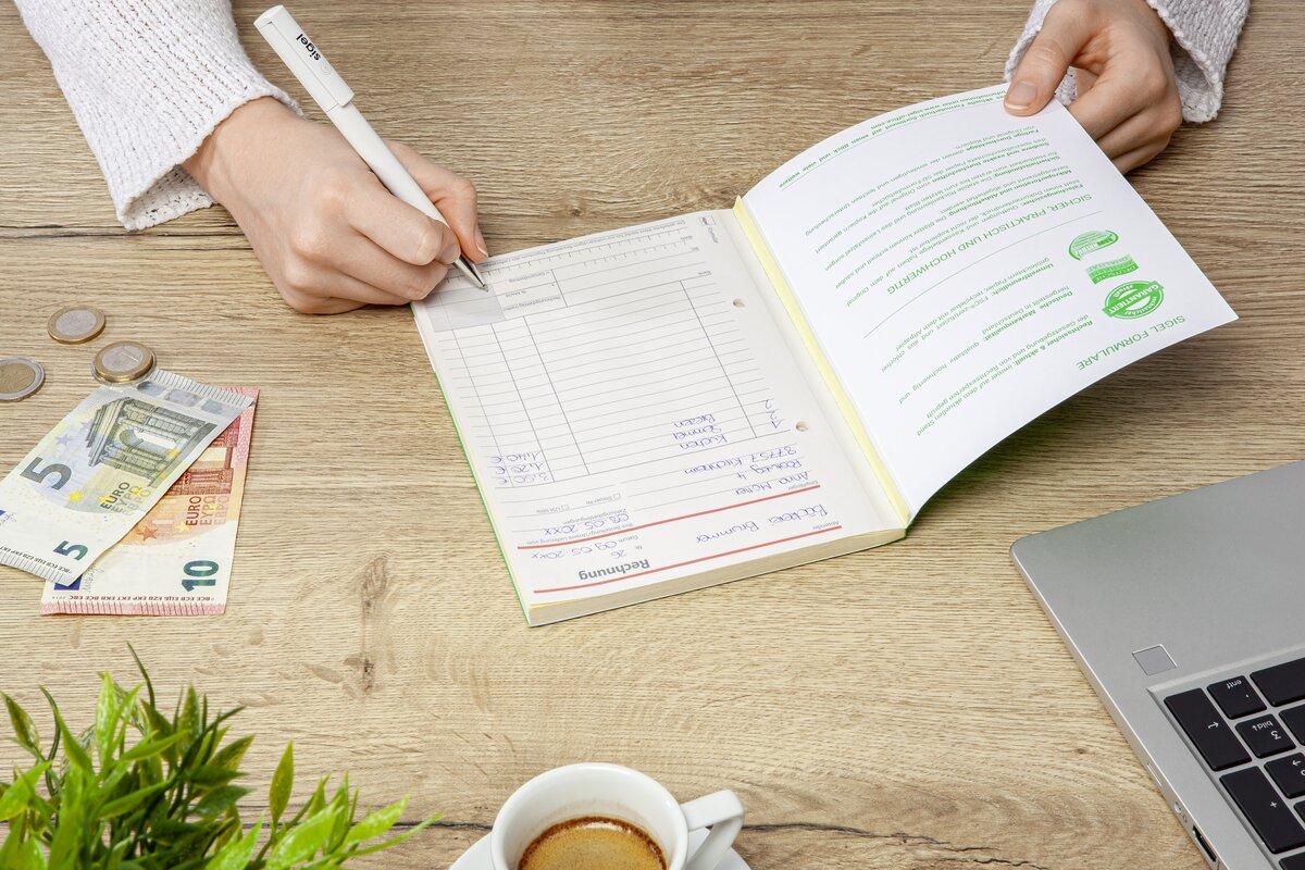 Personen schreiben in ein Heft, Geld liegt daneben