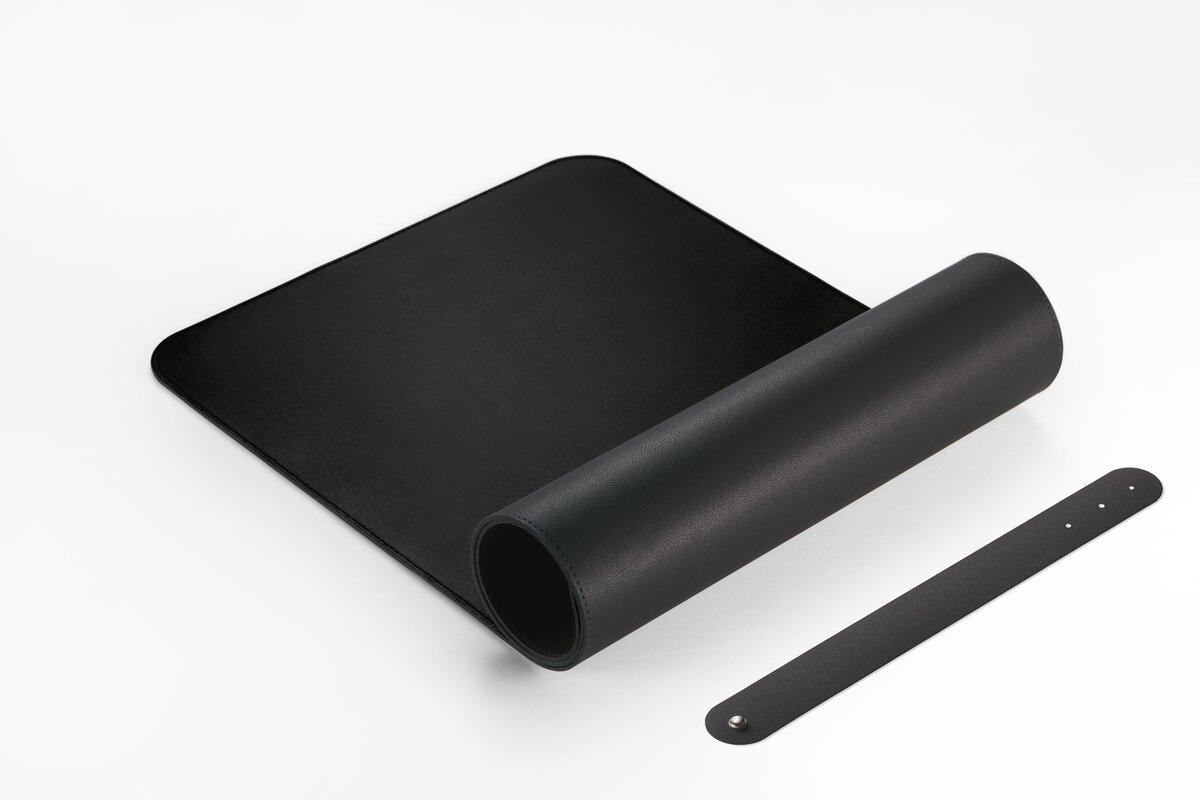 Schwarze Schreibtischunterlage, ausgerollt und gerollt, mit Halteriemen