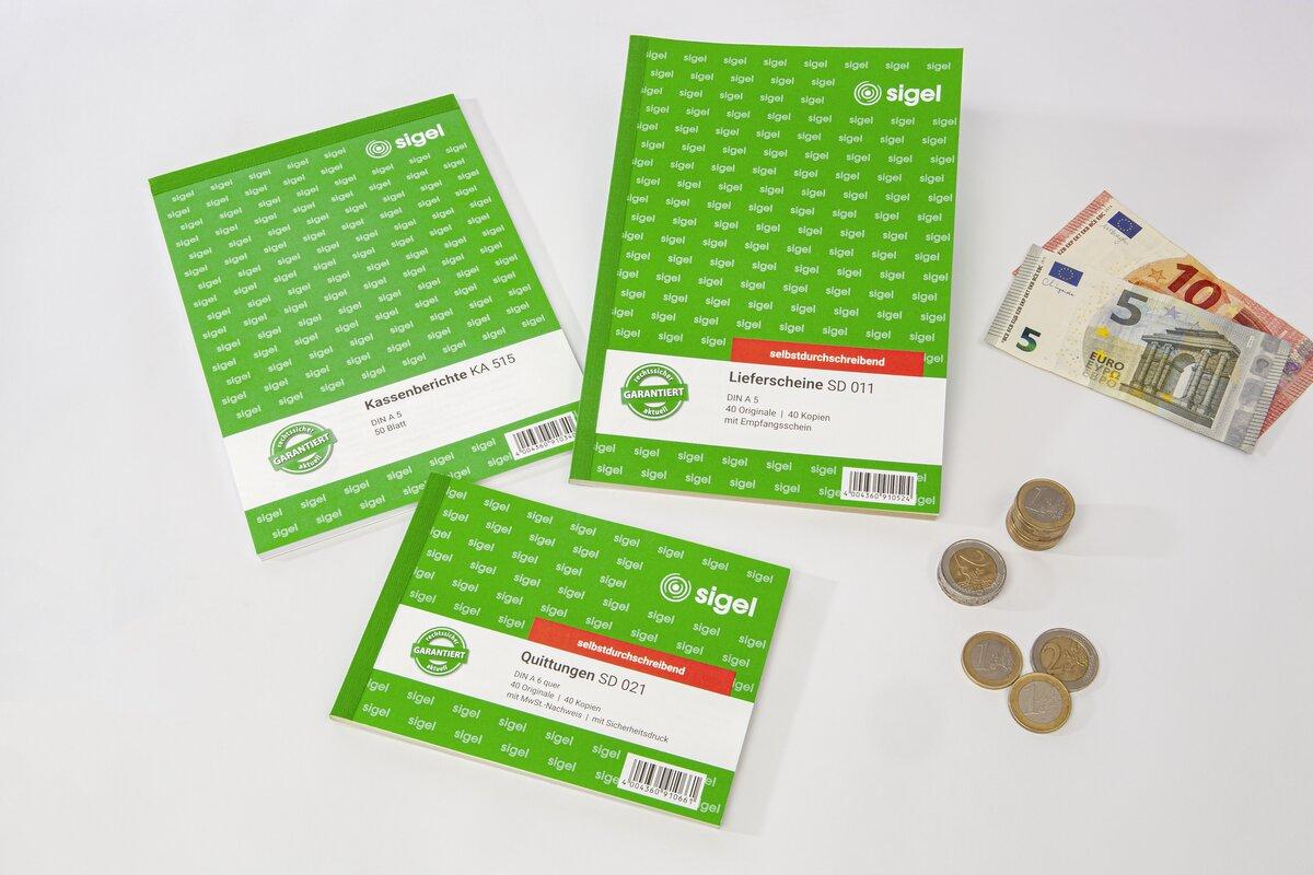 Grüne Schreibblöcke, Geldscheine und Münzen auf weißem Hintergrund