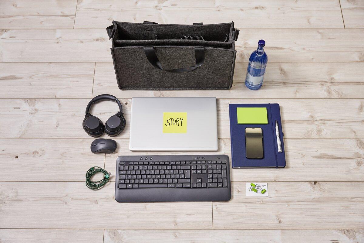 Laptop mit Story-Notiz, Kopfhörer, Tastatur, Maus, Kabel, Block, Stift, Flasche auf Holzboden