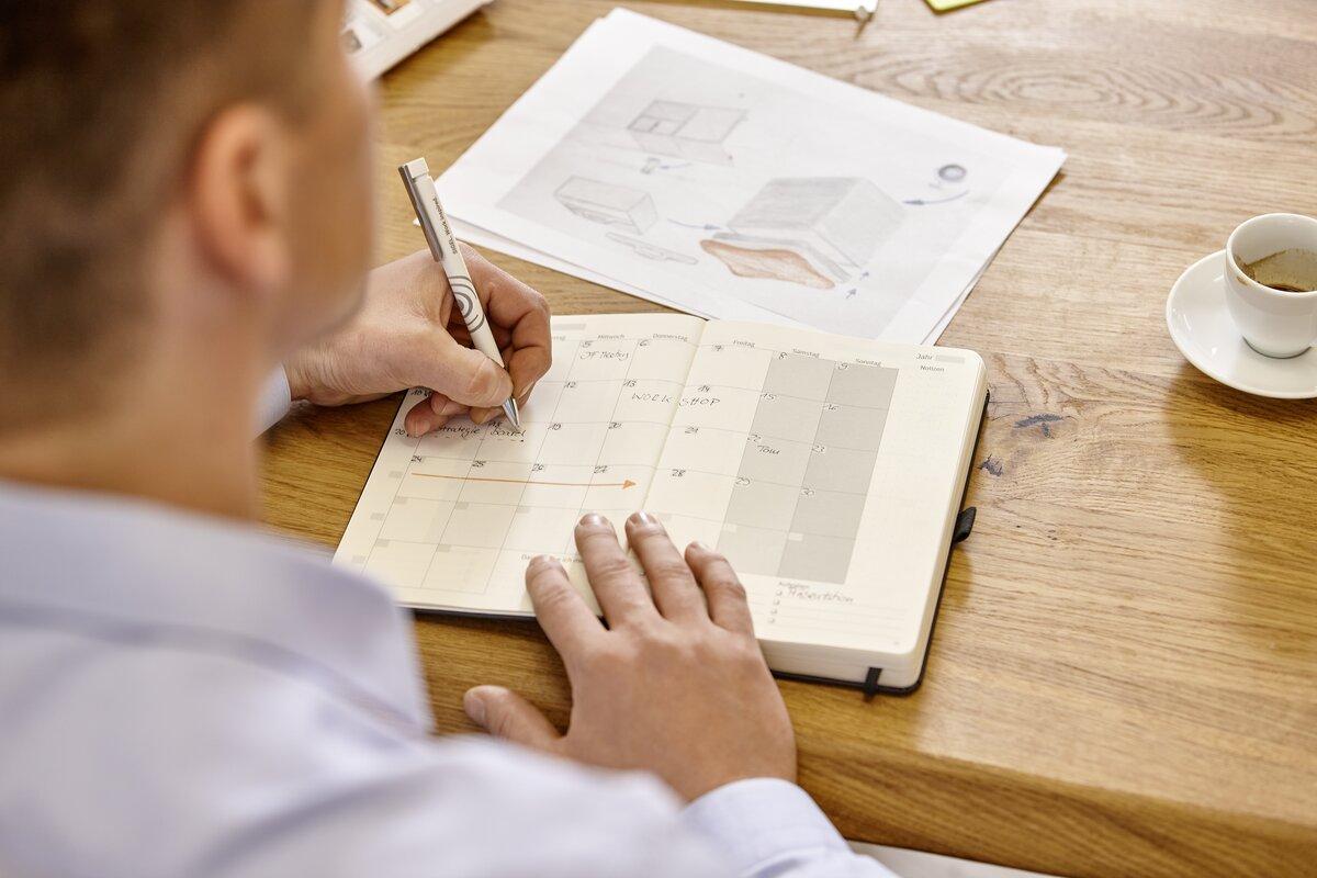 Kalender auf Tisch, Person schreibt