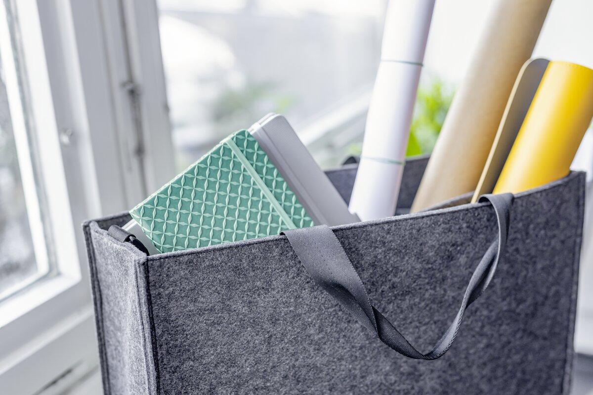 Graue Filztasche mit Rollen und Notizbuch