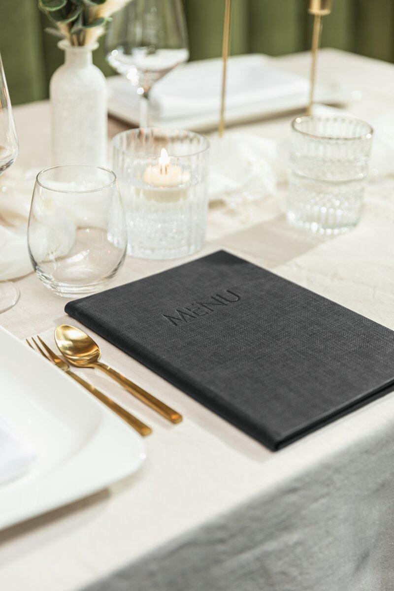 Menu on set table, gold cutlery