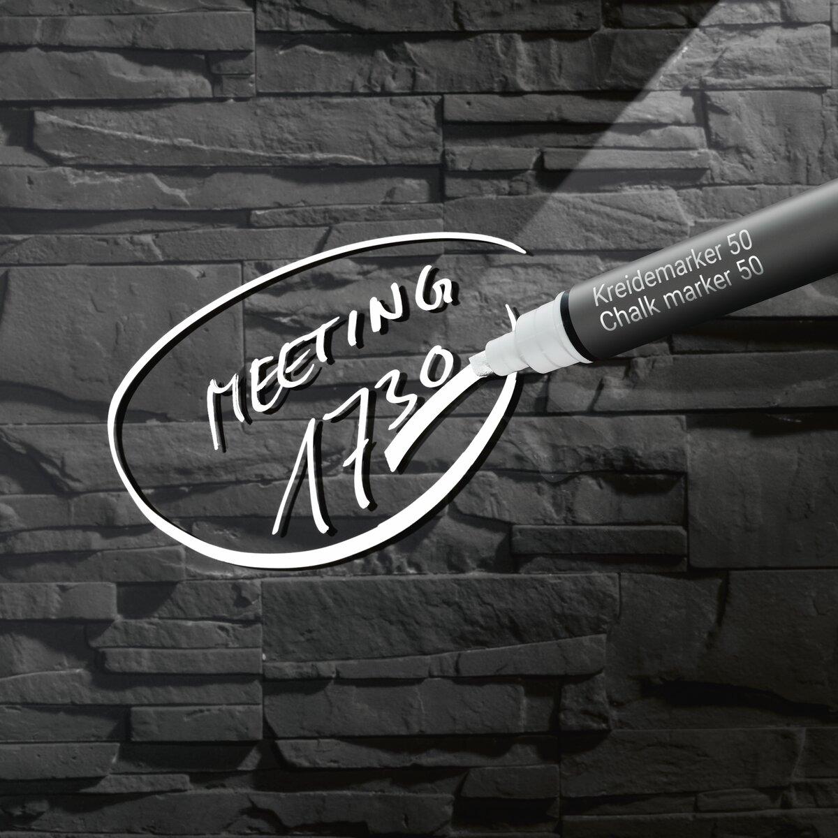 Meeting 17:30 written with chalk marker on black stone wall