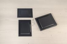 Schwarze Notizbücher und Büroklammern auf hellem Holztisch