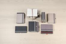 Notizbücher in verschiedenen Größen und Farben auf einem Holztisch Ein geöffnetes Buch in der Mitte