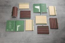 Verschiedene Notizbücher und Etuis in Holzoptik auf grauem Hintergrund angeordnet