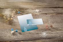 Two blue cards with polar bear motif on a wooden table, surrounded by decorations and artificial snow